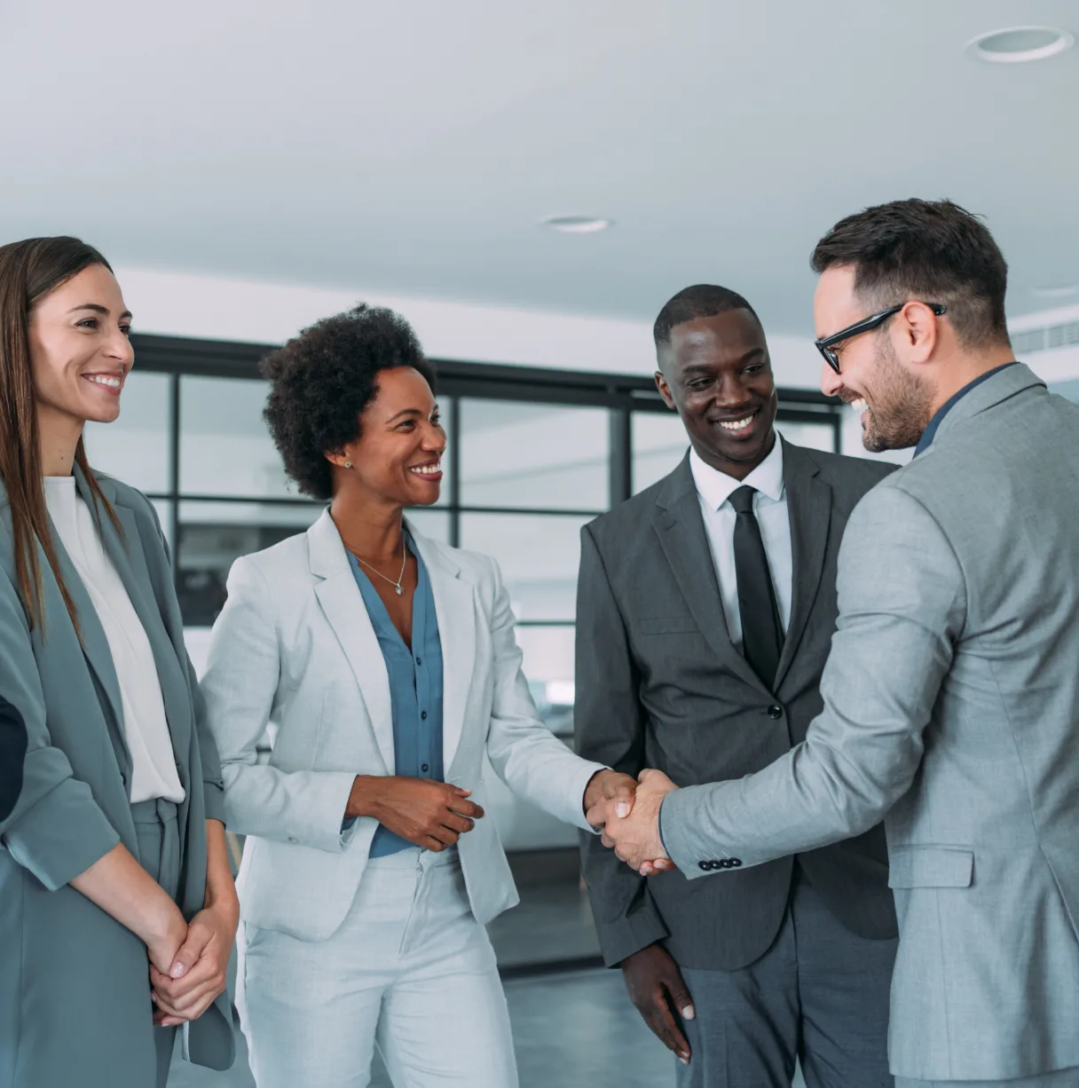 people in grey suits shaking hands smiling